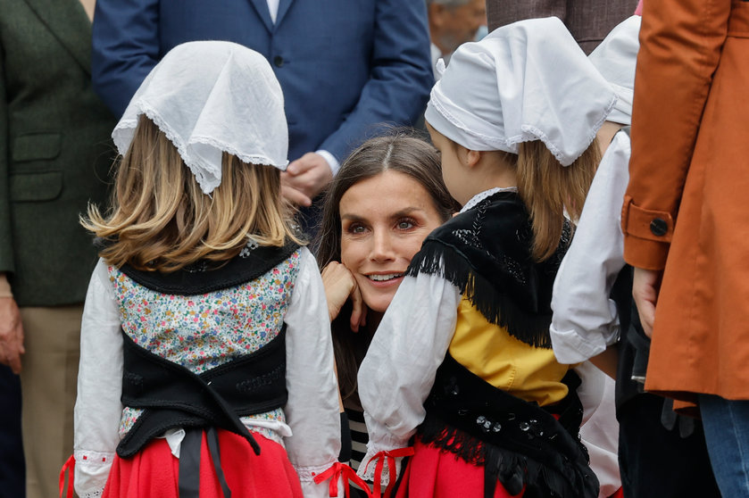 La reina Letizia conversa con dos niñas mientras durante la visita de la familia real a la parroquia de Cadavedo, en el municipio de Valdés, tras ganar el premio al pueblo ejemplar de Asturias, este sábado. EFE/ Ballesteros