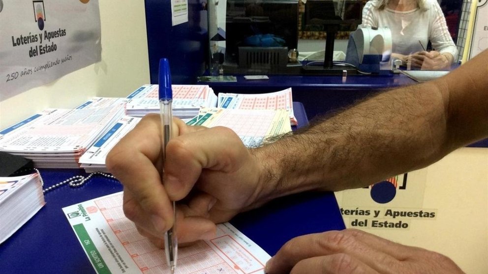 Un hombre rellena un boleto de Lotería Primitiva en una administración de loterías. ARCHIVO