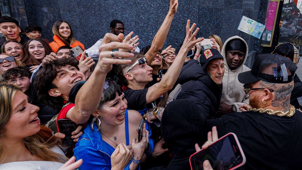 El rapero Yung Beef (c-d), rodeado de guardaespaldas, lanza billetes reales para promocionar su último trabajo, este jueves en el centro de Madrid. EFE/ Sergio Pérez