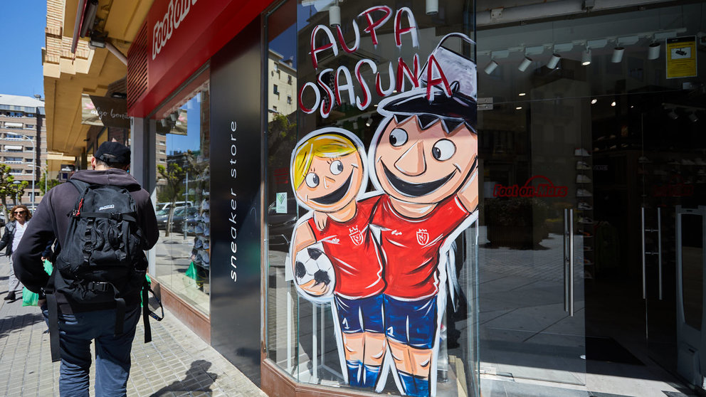 El pintor Alain Larreina y la Asociación Ensanche Área Comercial han creado la iniciativa de los escaparates rojillos para que los locales de la zona luzcan dibujos relacionados con la final de Copa del Rey de Osasuna. IÑIGO ALZUGARAY