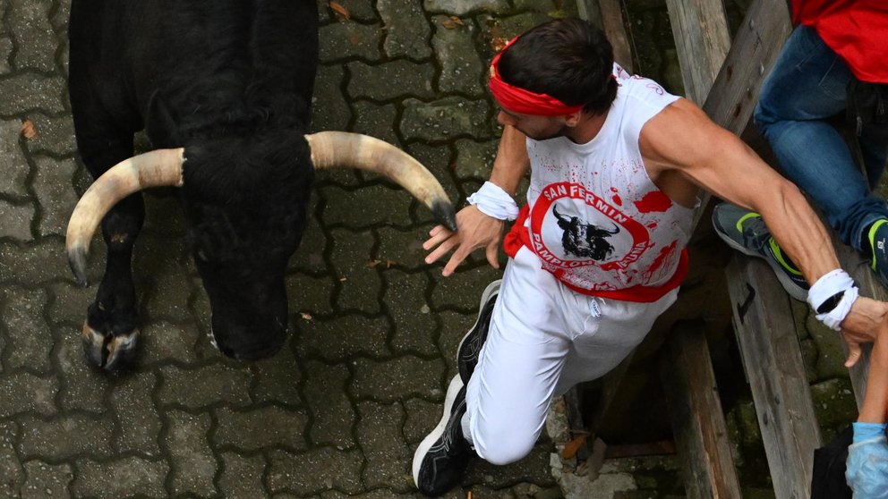 Un mozo acorralado por uno de los toros de Los toros de la ganadería La Palmosilla en el primer encierro de los sanfermines de este julio de 2023. EFE Eloy Alonso