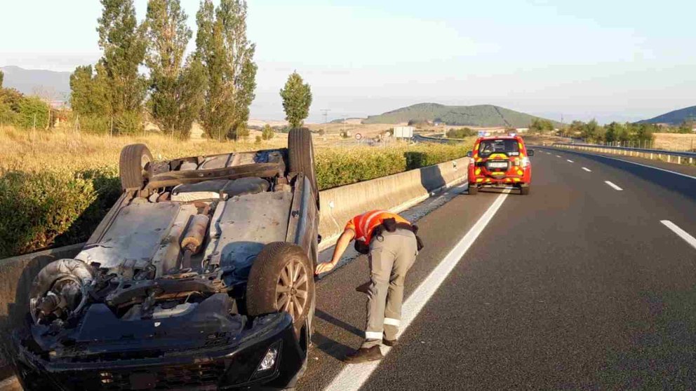 Un Policía Foral inspecciona el coche volcado en la Autovía del Pirineo. POLICÍA FORAL