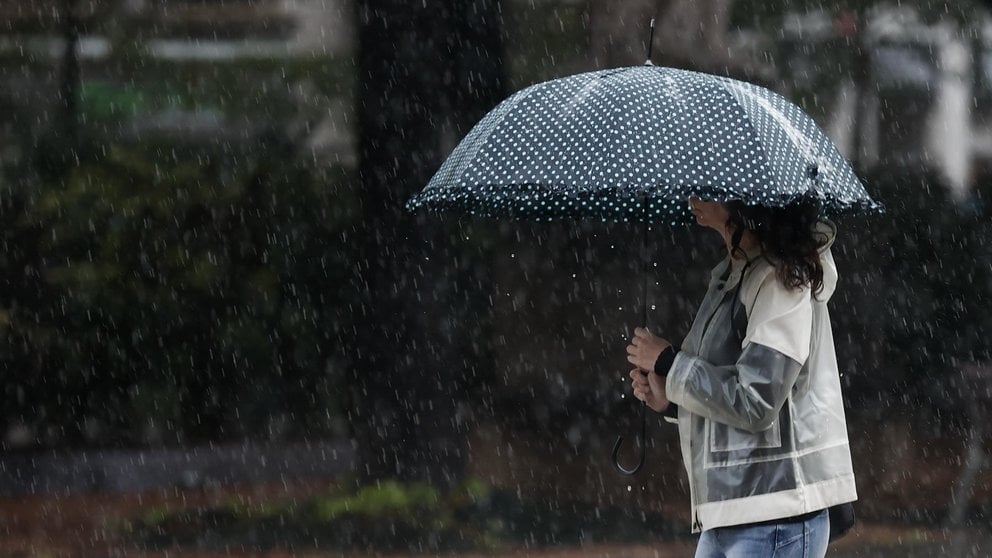 Una mujer se protege de la lluvia con un paraguas en una jornada donde el ambiente inestable, con chubascos localmente fuertes y de cierta intensidad continúa en la Comunidad Foral. EFE/ Jesús Diges