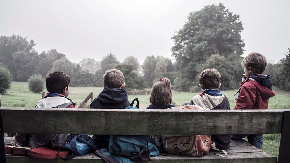 Un grupo de niños sentados en un banco. ARCHIVO