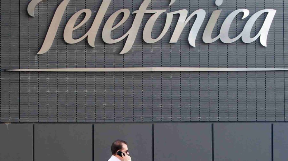 Un hombre habla por teléfono móvil pasando ante una sede de Telefónica. ARCHIVO