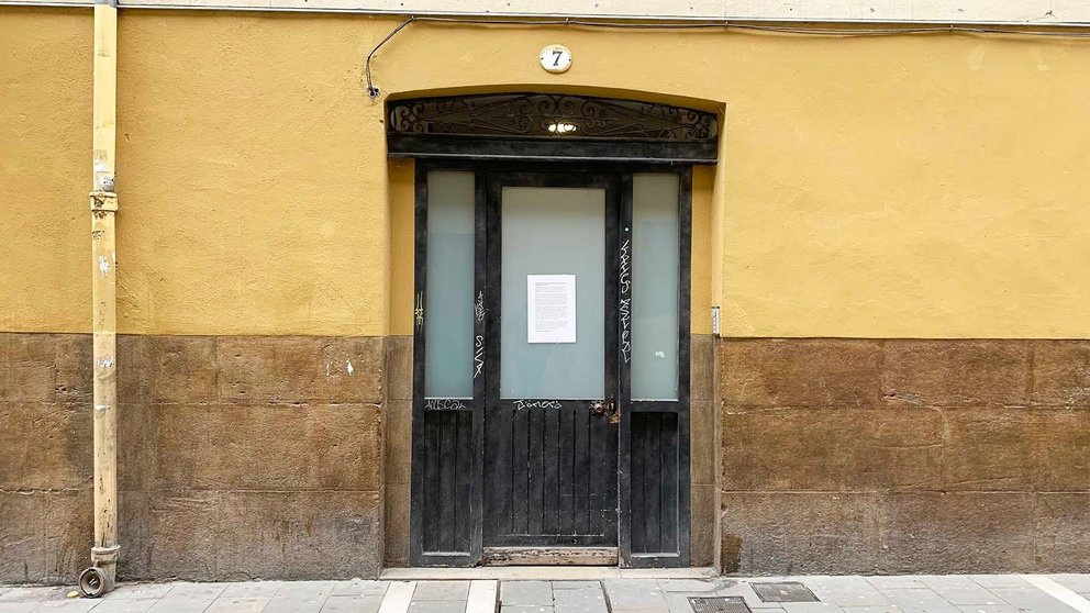 Portal de entrada al número 7 de la calle Eslava de Pamplona con el cartel colocado en el cristal. Navarra.com