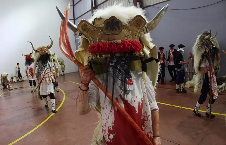 Los Momotxorros, niños y adultos, cubiertos de sangre de animal y ataviados con cuernos, pieles y su gran sarde de madera, recorren las calles de Alsasua al anochecer bailando y asustando a todo aquel que se cruce en su camino durante el carnaval rural de la localidad. IÑIGO ALZUGARAY