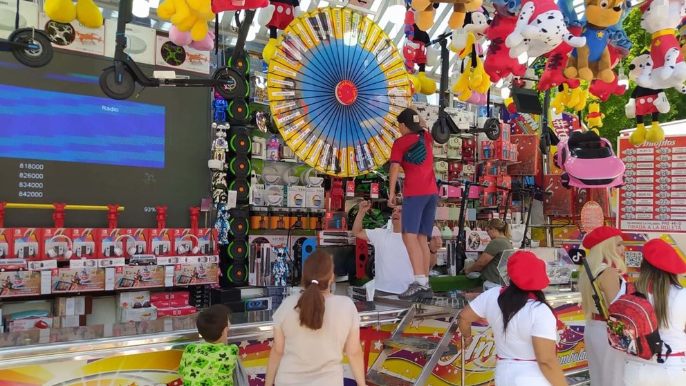 Un joven probando suerte en la ruleta de la Tómbola Antojitos con Agosti Ortega al tras el mostrador. NAVARRA.COM