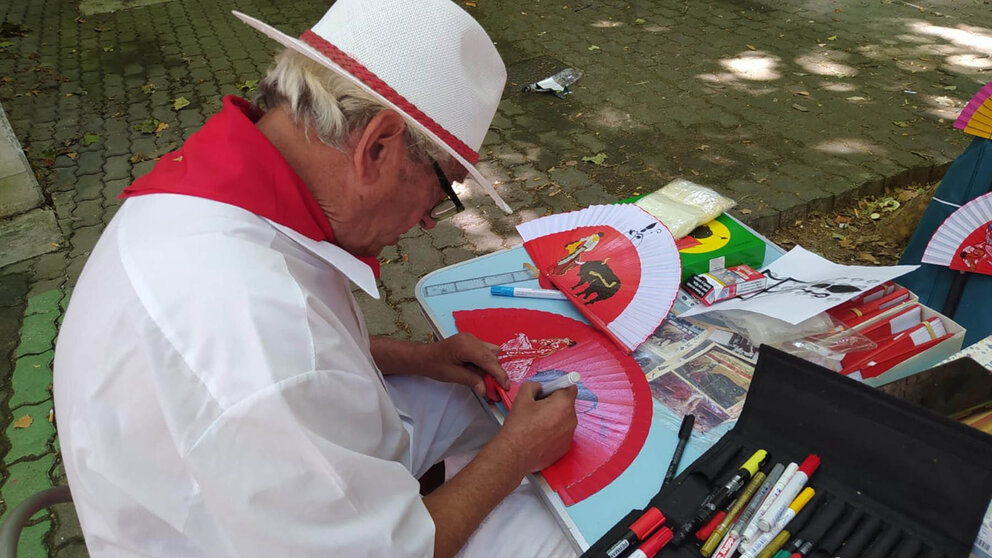 Joaquín Martínez pintando uno de sus populares abanicos al lado de la plaza de toros de Pamplona. NAVARRA.COM