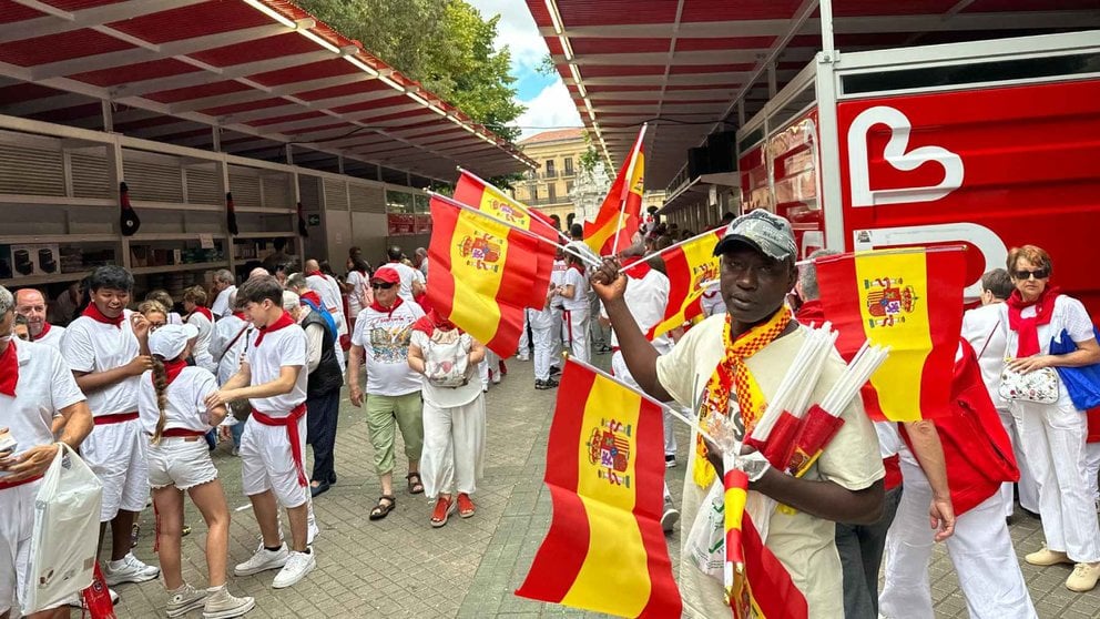 Un vendedor ambulante vende banderas de España junto a la Tómbola en San Fermín. NAVARRA.COM