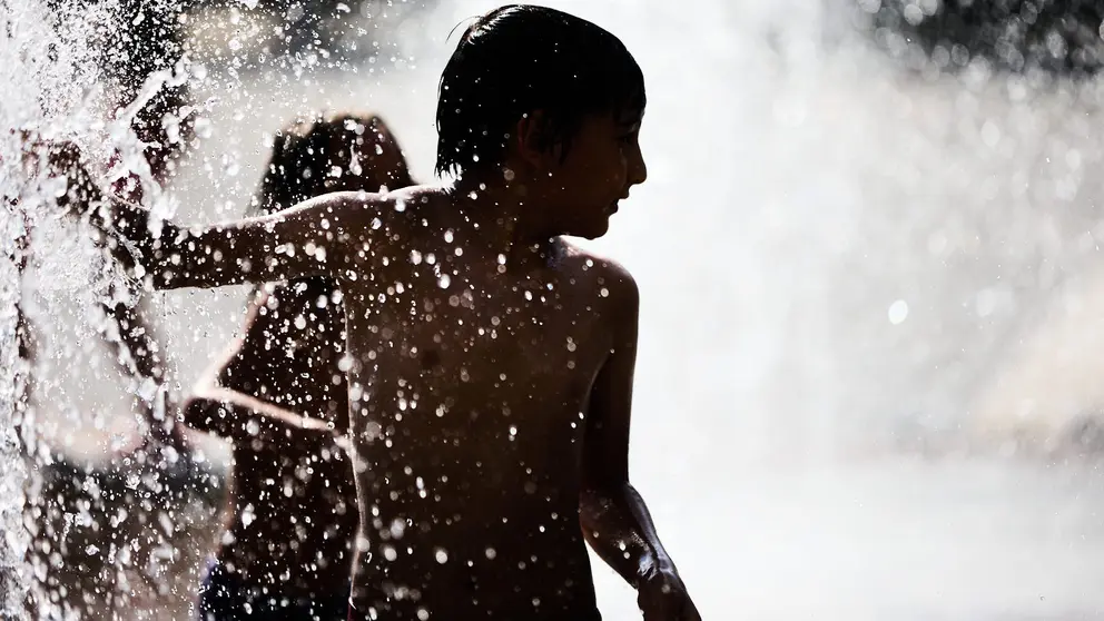 Unos niños juegan en la Fuente de los Chorros en el parque de Yamaguchi de Pamplona en el primer día de una nueva ola de calor de este verano. IÑIGO ALZUGARAY