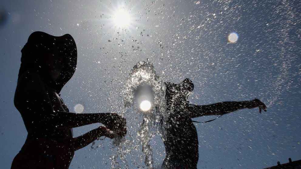 Varios jóvenes se refrescan en la fuente de la Plaza Yamaguchi de Pamplona en una jornada en la que la comunidad Foral se encuentra en alerta naranja por la primera ola de calor que afecta a más de media España. EFE/Iñaki Porto