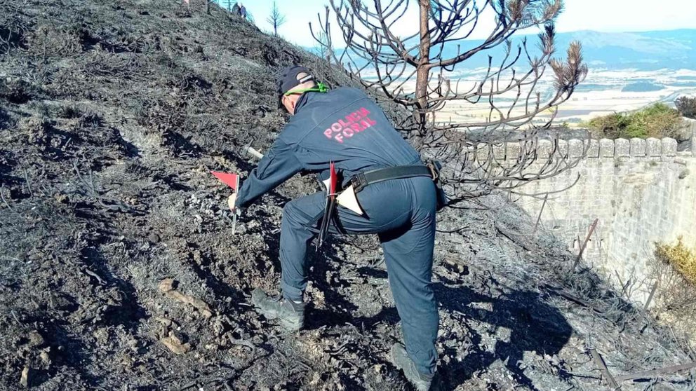 Un agente de la Policía Foral recoge muestras en los restos del incendio del Fuerte de San Cristóbal. POLICÍA FORAL