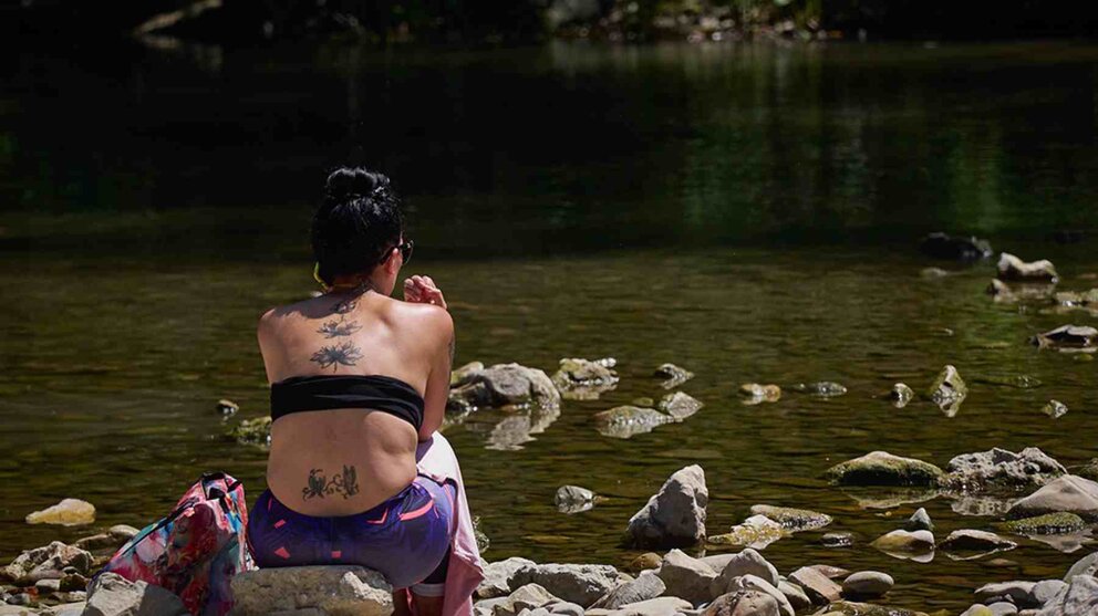 Una joven disfruta a orillas del río tras un baño. EUROPA PRESS