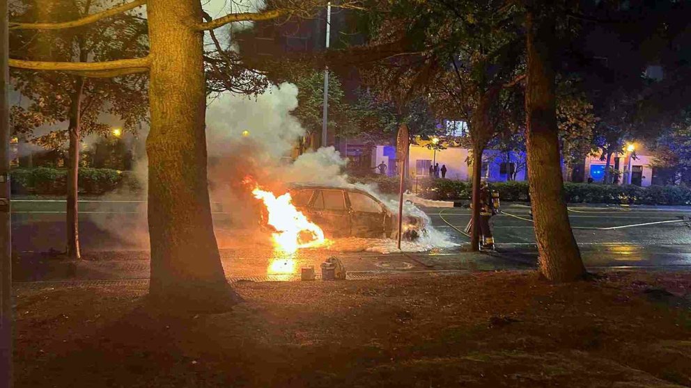 Un bombero termina de apagar el coche que salió ardiendo en la Avenida de Navarra. POLICÍA MUNICIPAL DE PAMPLONA