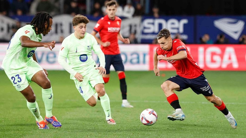 El delantero de Osasuna Brian Zaragoza (d) juega un balón ante Pablo Torre (2-i) y Jules Koundé (i), ambos del Barcelona, durante el partido de LaLiga en Primera División que CA Osasuna y FC Barcelona disputan este sábado en el estadio de El Sadar, en Pamplona. EFE/Villar López