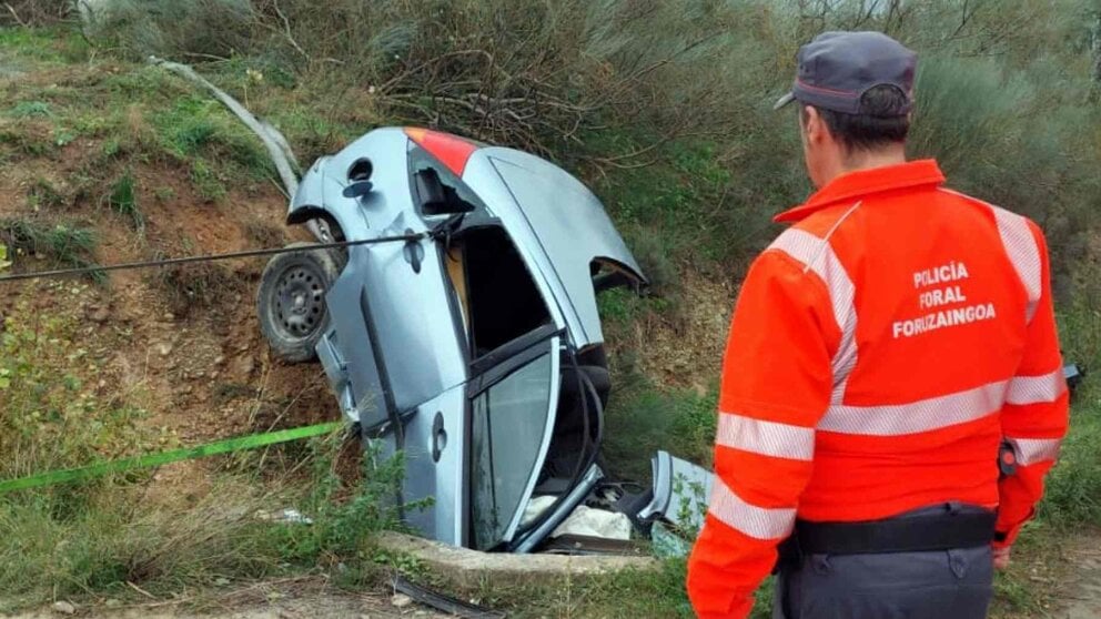 Un agente de la Policía Foral ante el coche siniestrado en el que viajaba el fallecido. POLICÍA FORAL