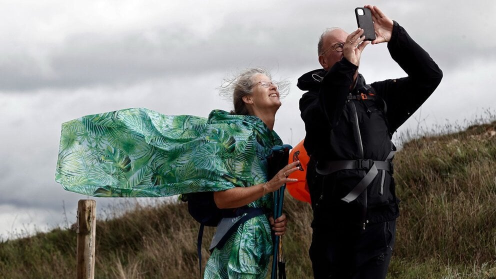 Dos peregrinos que realizan el Camino de Santiago se toman un fotografía en el alto de El Perdón donde el fuerte viento levanta al vuelo la capa de uno de ellos. Este miércoles se esperan en Navarra lluvias y chubascos generalizados que pueden ser fuertes e ir acompañados de tormenta a partir de mediodía y rachas de viento muy fuertes en la primera mitad del día en las zonas de montaña del norte. Así lo indica la Agencia Estatal de Meteorología que anuncia cielos nubosos o cubiertos, con brumas y probables nieblas al principio y final del día en zonas elevadas. EFE/ Jesus Diges