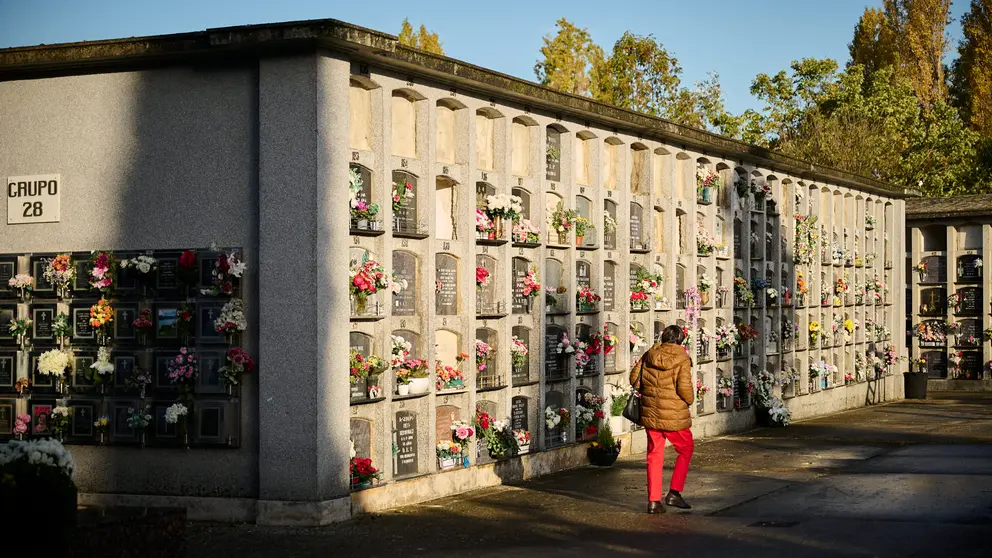 Varias personas llevan flores a sus sere queridos durante la celebración de Todos los Santos en el cementerio de Pamplona. PABLO LASAOSA