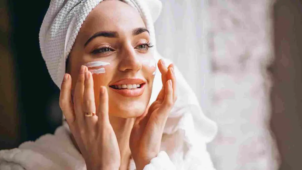 Mujer aplicándose crema en la cara.