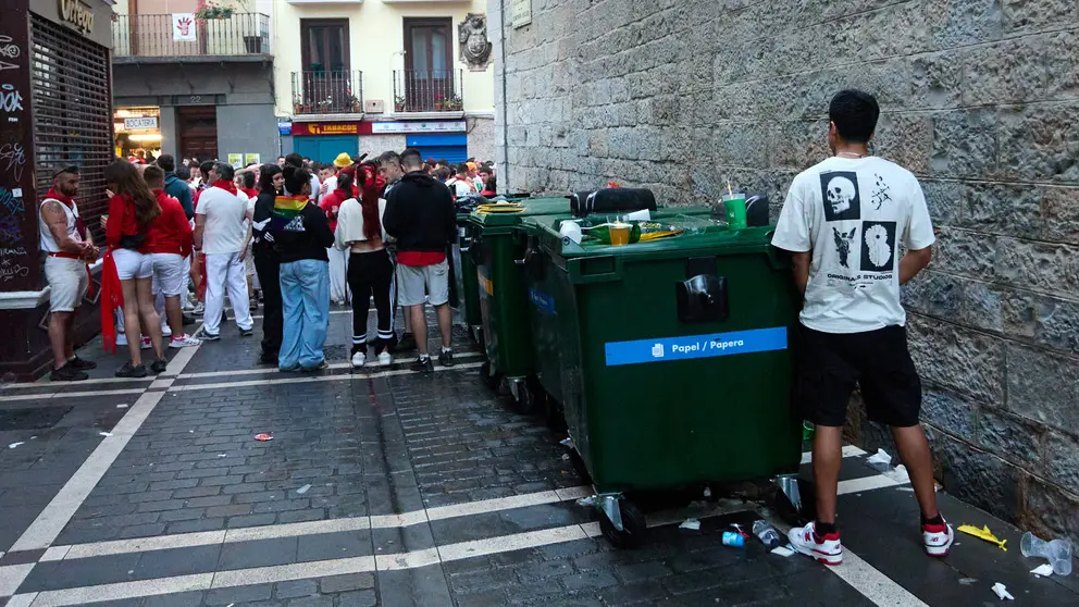 Un joven orina junto a unos contenedores en los momentos previos al inicio de las dianas de San Fermín. IÑIGO ALZUGARAY