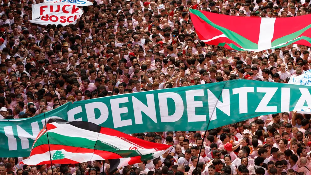 Bandera palestina (abajo), pancarta proindependentista (c) e ikurriña (arriba), al inicio de los Sanfermines en la Plaza Consistorial con el Chupinazo desde el balcón del ayuntamiento de Pamplona, este domingo. EFE/ Jesús Diges