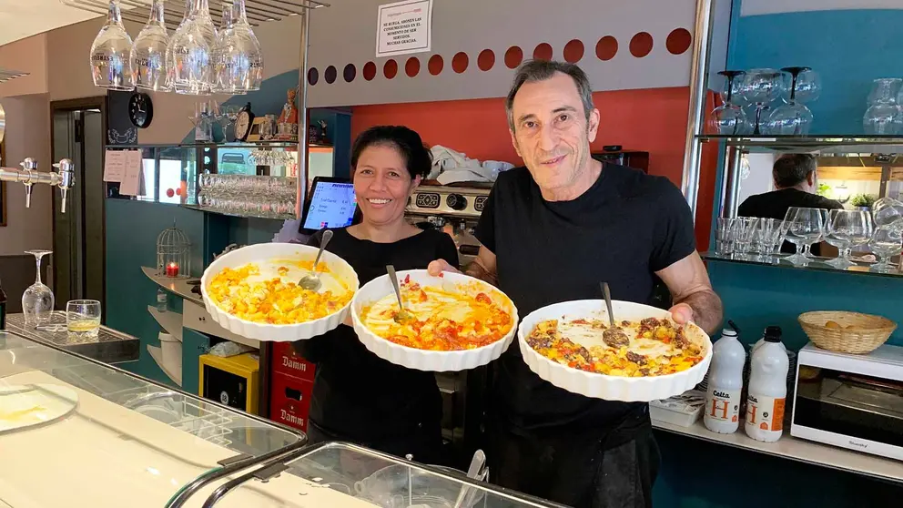 Sulema Flores y Patxi Domínguez sostienen bandejas con huevos rotos en el bar Txipi Txapa. Navarra.com