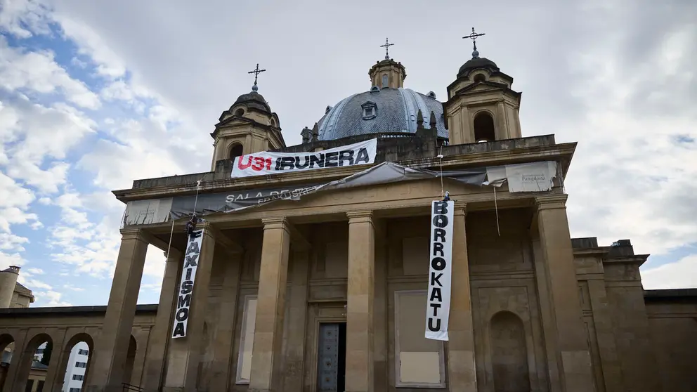 Dos personas se cuelgan del monumento a Los Ca&iacute;dos de Pamplona en la Plaza de la Libertad. PABLO LASAOSA