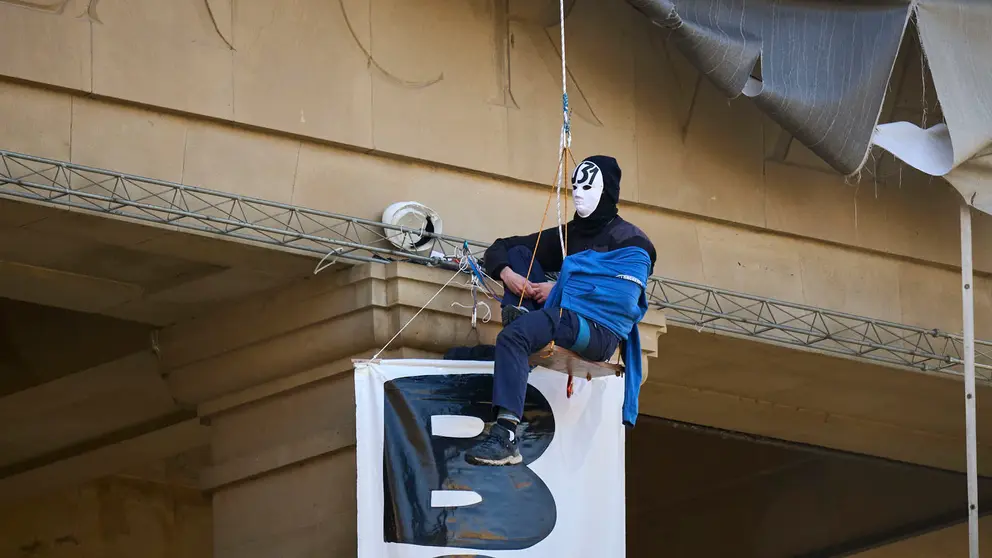 Dos personas se cuelgan del monumento a Los Ca&iacute;dos de Pamplona en la Plaza de la Libertad. PABLO LASAOSA