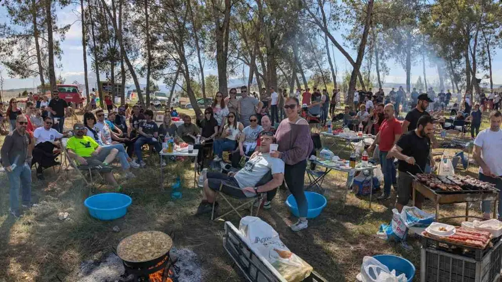 Personas celebrando una barbacoa multitudinaria en un entorno natural.