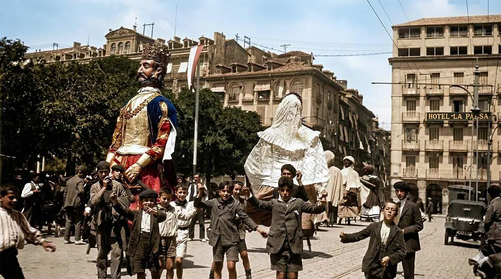 Desfile de la Comparsa en la Plaza del Castillo, procedente de la calle Chapitela. Grupo de ni&ntilde;os bailan de cara al fot&oacute;grafo. Al fondo el Hotel La Perla. (Fotograf&iacute;a restaurada del Archivo Municipal de Pamplona).
