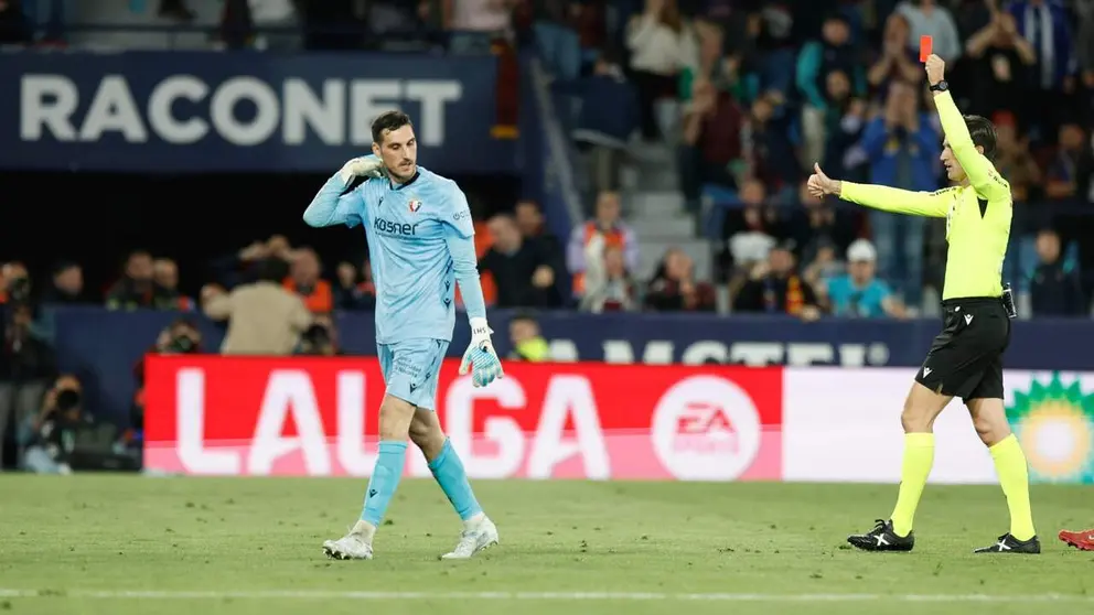 El portero de Osasuna Sergio Herrera (izda) es expulsado por el colegiado del encuentro Munuera Montero, durante el partido de la jornada 35 de LaLiga EA Sports disputado este viernes entre el UD Levante y el CA Osasuna en el estadio Ciudad de Valencia. EFE/Kai Forsterling.
