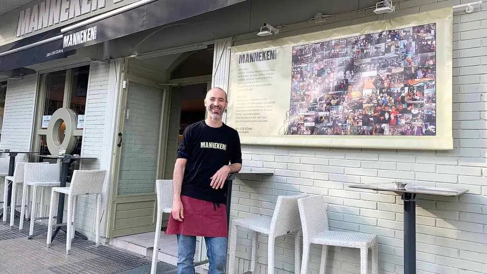 Eneko M&eacute;ndez junto al cartel que ha colocado en la fachada de su cervecer&iacute;a en Pamplona. Navarra.com