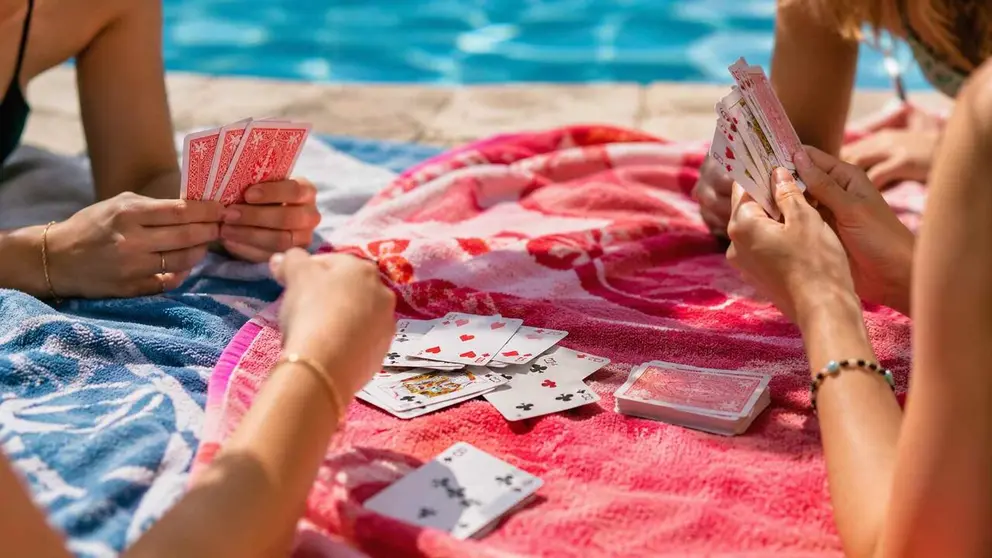 Imagen generada con IA de unas chicas jugando a las cartas en una piscina. CHAT GPT