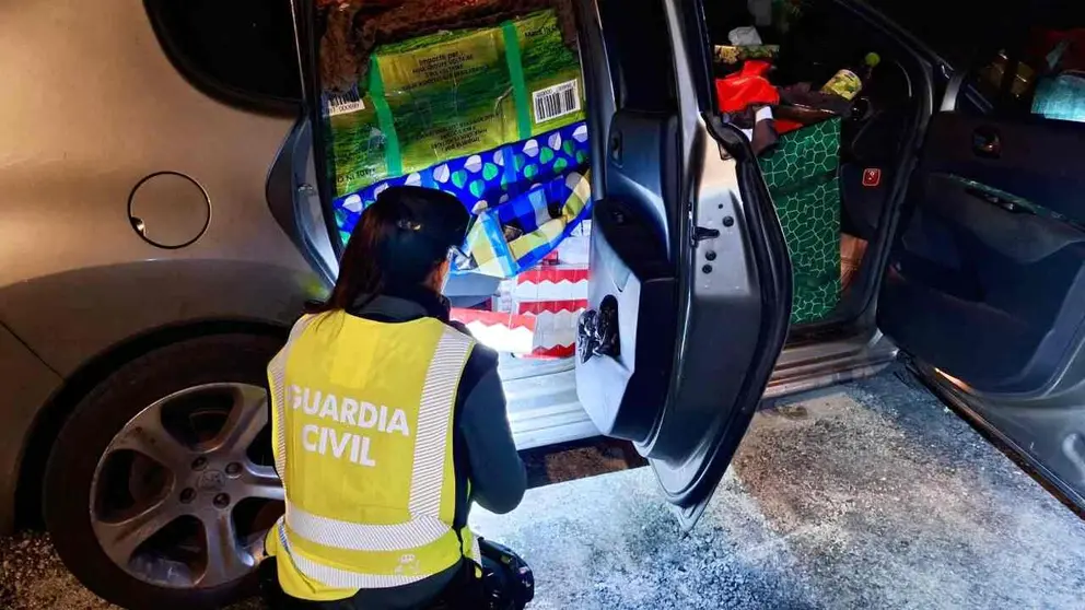 Un agente de la Guardia Civil ante el veh&iacute;culo cargado de tabaco de contrabando. GUARDIA CIVIL