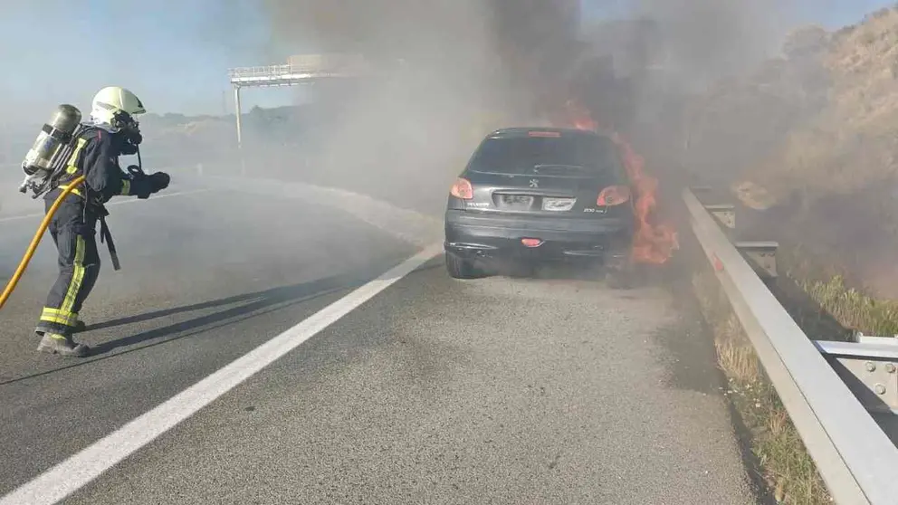 Un bombero extingue el incendio en el coche en medio de la Autopista de Navarra. BOMBEROS