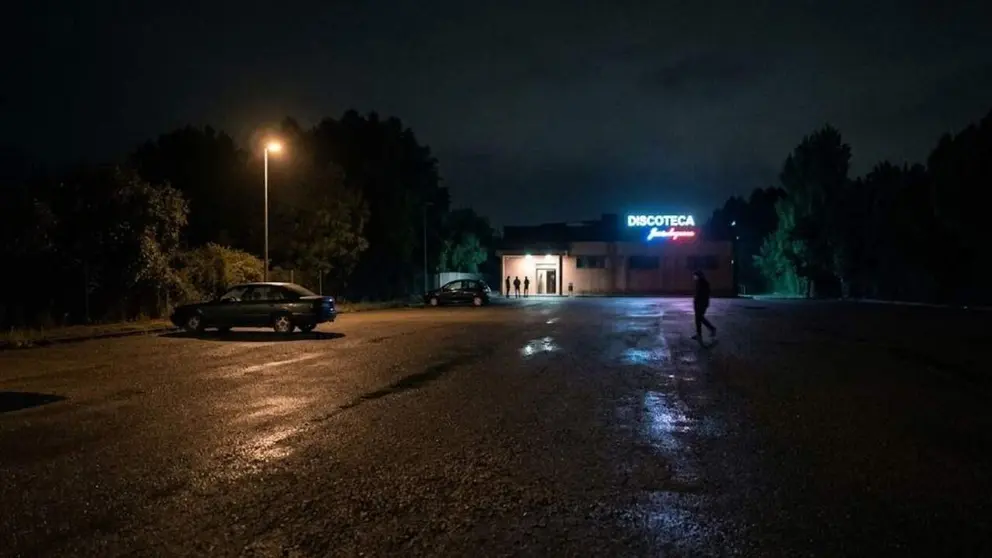 Vista nocturna del aparcamiento de una discoteca.