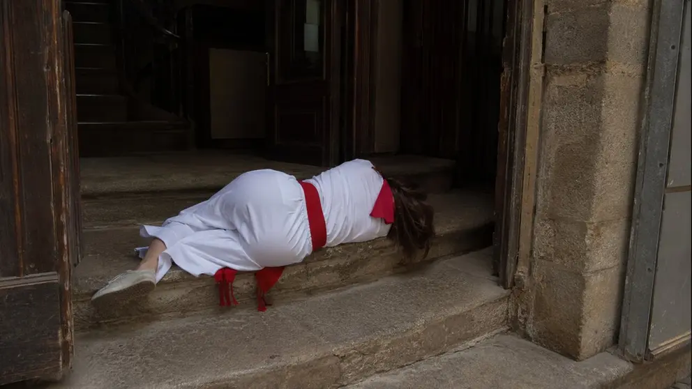 Imagen generada con Inteligencia Artificial de una mujer vestida de pamplonica y dormida en las escaleras de un portal. CHAT GPT