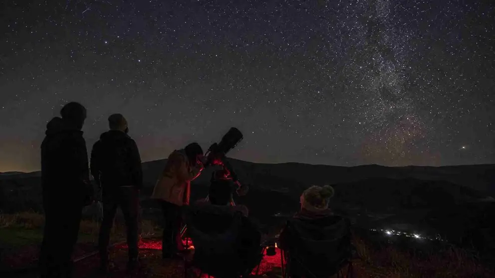 Varias personas observando el cielo con un microscopio en el campo.