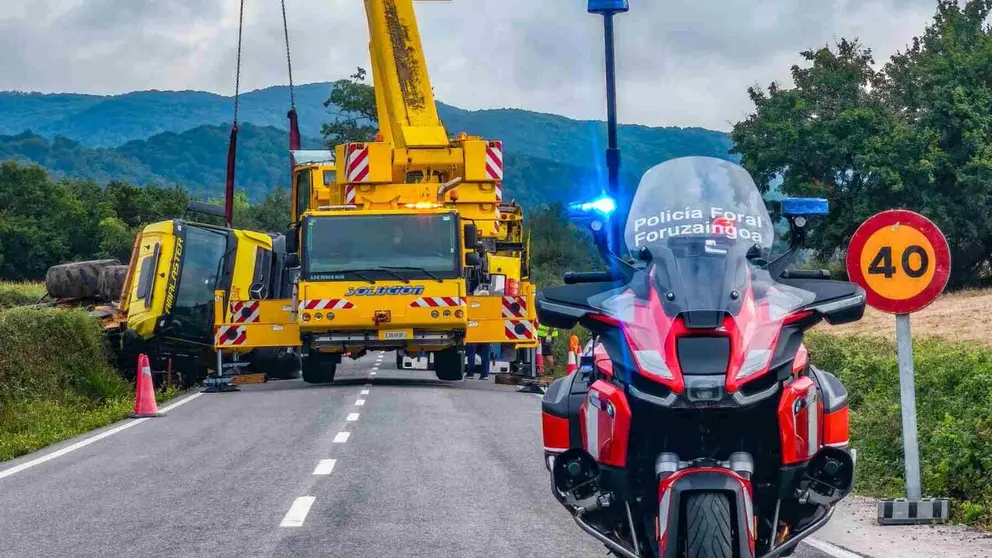 Una gr&uacute;a intenta retirar el cami&oacute;n accidentado. POLIC&iacute;A FORAL