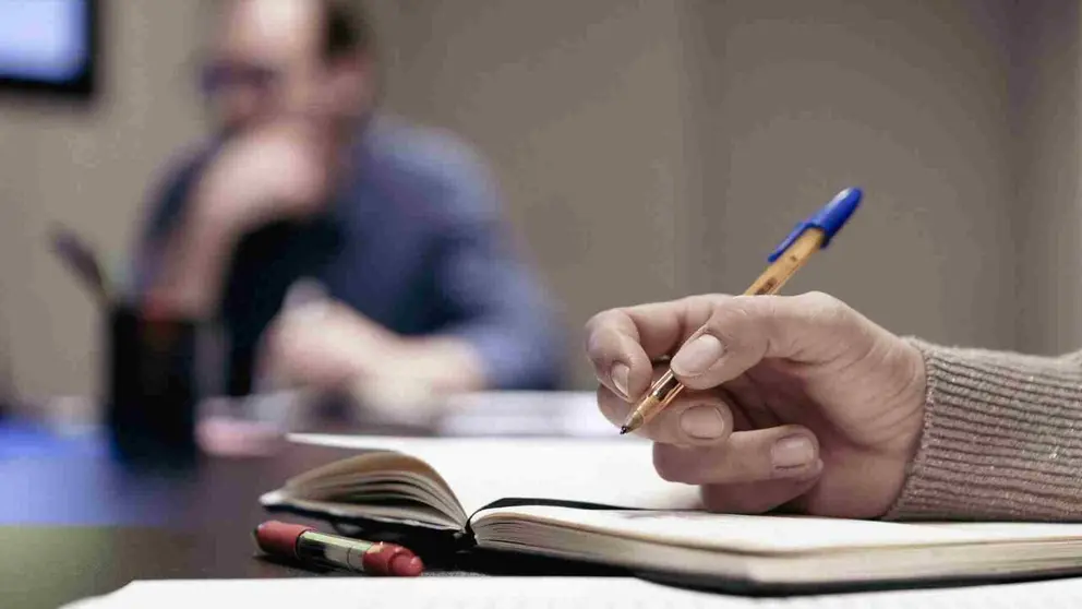 Una mujer escribe con bol&iacute;grafo en un cuaderno. CIVICAN