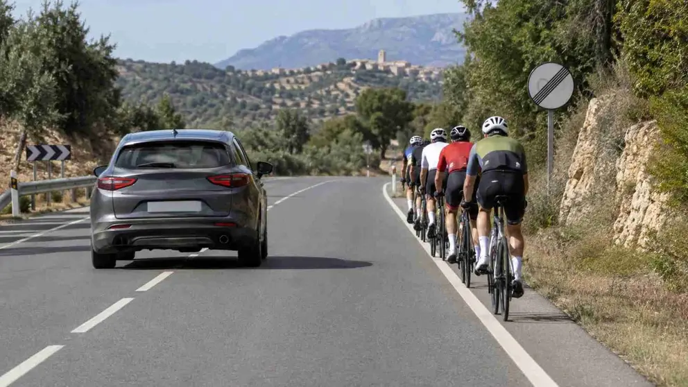 Un coche adelantando a un grupo de ciclistas en una carretera convencional.