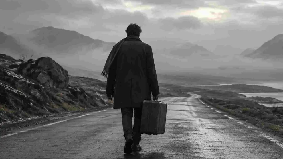 Un hombre abandona su pueblo con una maleta.