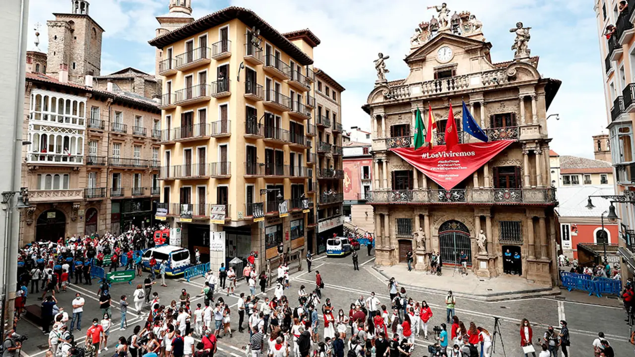GRAFCAV6974. PAMPLONA, 06/07/2020.-  Aspecto que presenta este lunes la Plaza del Ayuntamiento de Pamplona a las doce del mediodía del 6 de julio, el momento más esperado por los pamploneses, en el que debían dar inicio los Sanfermines de 2020, donde se ha desplegado un gran pañuelo rojo emplazando a las fiestas del próximo año con el lema "Los Viviremos".El momento esperado en la plaza Consistorial por un número controlado de personas, debido a la limitación de aforo establecida con motivo de la COVID-19, ha sido seguido con aplausos y gritos, unas muestras de alegría y tristeza, a la vez, que se han sucedido en diferentes puntos de la ciudad, donde numerosos pamploneses han quedado como es habitual en estas fechas para almorzar. EFE/ Jesús Diges
