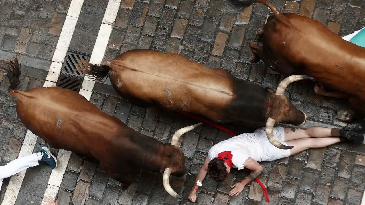 Un mozo es sobrepasado por los toros en el tramo de Mercaderes del primer encierro de los sanfermines de este julio de 2023 con toros de la ganadería de Palmosilla. EFE/ Jesús Diges