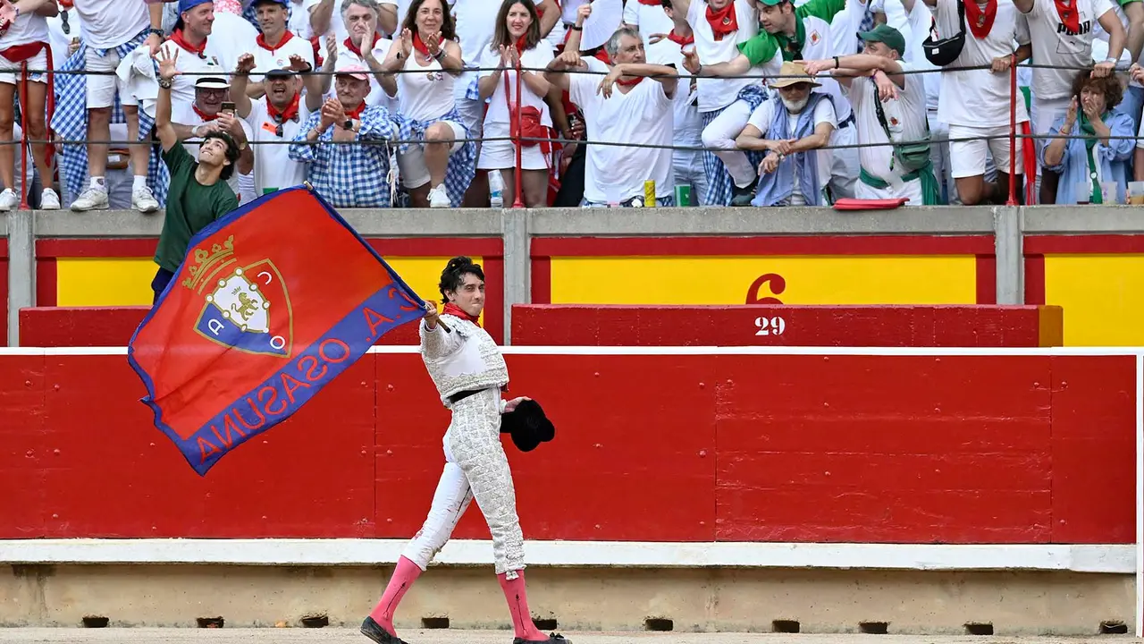 El diestro Andr&eacute;s Roca Rey da la vuelta al ruedo con una bandera de Osasuna. Roca Rey ha salido por la puerta grande de la plaza de Toros de Pamplona despu&eacute;s de cortar tres orejas a sus dos toros en suerte dentro de la Feria del Toro de los Sanfermines 2023, donde ha compartido cartel con Morante de la Puebla y Alejandro Talavante con toros de la ganader&iacute;a gaditana de N&uacute;&ntilde;ez del Cuvillo.    EFE/Eloy Alonso