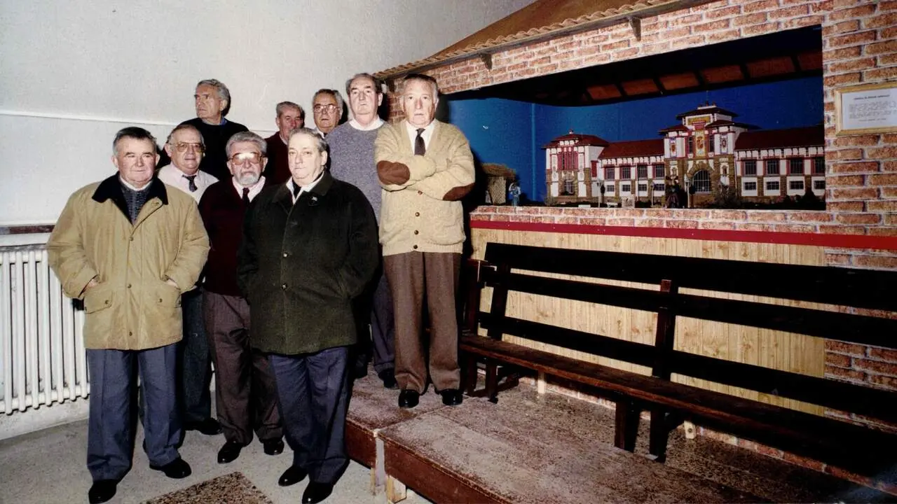 Fotograf&iacute;a del a&ntilde;o 96 en la que aparecen varios miembros de la Asociaci&oacute;n de Belenistas junto al Bel&eacute;n Parroquial que realizaron en la Iglesia San Andr&eacute;s con la maqueta de la Escuela de Peritos Agr&iacute;colas de Navarra que se encuentra actualmente en el Sal&oacute;n de Plenos del Ayuntamiento. CEDIDA