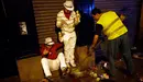 Revellers react as a municipal worker sweeps garbage from under their feet while they wait for the start of the fifth running of the bulls at the Estafeta corner during San Fermin festival in Pamplona July 11, 2012. Several runners suffered light injuries in a run that lasted three minutes and twelve seconds, according to local media. REUTERS/Susana Vera (SPAIN - Tags: SOCIETY TPX IMAGES OF THE DAY) SPAIN/