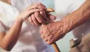 Una cuidadora ayuda a caminar a una persona mayor con un bastón. ARCHIVO
