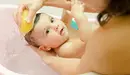 Una madre baña a su bebé en una bañera y le frota la cabeza con una esponja ARCHIVO